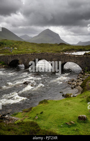 Sligachan alte steinerne Brücke über den Fluss mit Sligachan Marsco Peak von Red Cuillin Mountains nach einem Sturm Isle of Skye Schottland Großbritannien Stockfoto