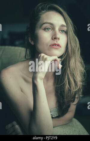 Eine blonde Frau sitzt in Gedanken verloren Stockfoto