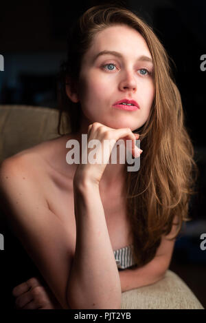 Eine blonde Frau sitzt in Gedanken verloren Stockfoto