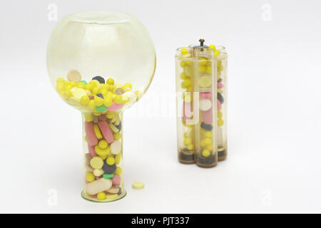 Bunte Pillen oder Tabletten in upside-down gelb Glas lab Kolben und Reagenzgläser in Kunststoffhalter, verschwommenes auf Hintergrund Stockfoto