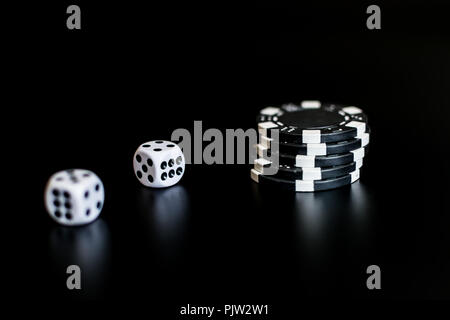 Würfel und monochrome Casino Chips auf schwarzem Hintergrund. Stockfoto