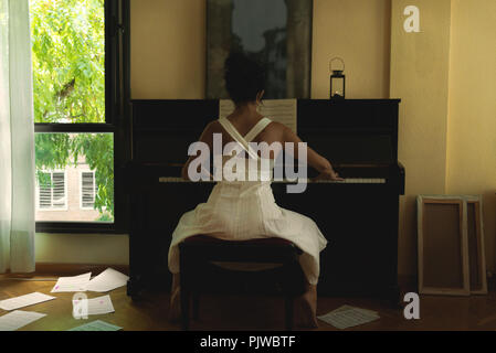 Frau in weißem Kleid Klavier spielen Stockfoto