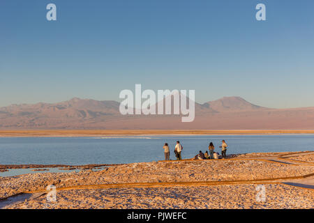 Atacama, Chile - Okt 9 2017 - Gruppe der Touristen schätzen den Sonnenuntergang in der Wüste von Atacama Salzsee, blaue Wasser, Vulkan im Hintergrund, warm Stockfoto