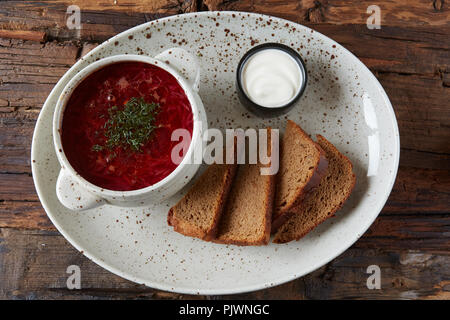 Traditionelle ukrainische Russischen Borschtsch mit weißen Bohnen auf die Schüssel. Platte von Rot Rote Beete Suppe Borschtsch auf Schwarz rustick Tabelle. Rote-bete-Suppe Ansicht von Oben. Traditionelle ukrainische Essen Küche Stockfoto