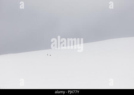 Ein sehr minimalistisches Blick auf zwei weit entfernte Menschen über einen Berg von Schnee bedeckt Stockfoto