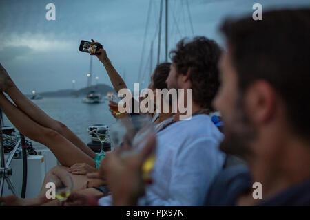 Vier Freunde auf dem Boot in der Dämmerung sitzen, Wein trinken, wobei selfie, Britische Jungferninseln Stockfoto