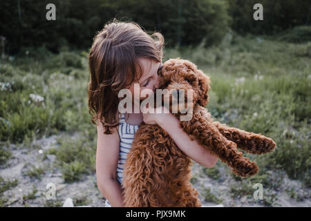 Mädchen küssen Welpen in die Arme Stockfoto