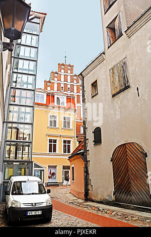 RIGA, Lettland - 28. AUGUST 2018: die mittelalterliche Straße in der Altstadt von Riga, Lettland. Blick auf Saint John's Kirche (rotes Gebäude) andold Industriebau (links) Stockfoto