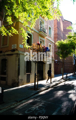 Man Walking entlang der sonnenbeschienenen Barcelona Straße. Ruhige Szene mit Schatten von Bäumen. Stockfoto