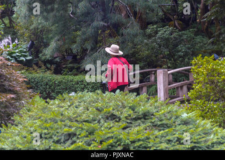 Asiatische Besucher im Stroh Hut in, Japanischer Garten, die Butchart Gardens, Brentwood Bay, British Columbia, Kanada Stockfoto