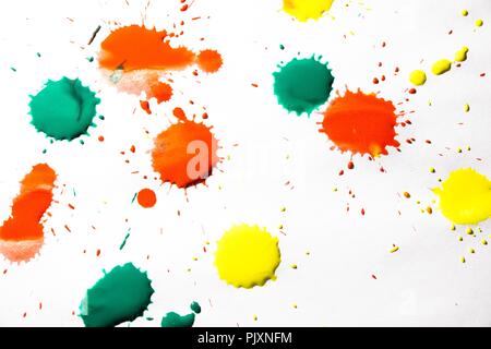 Tropfen rote, gelbe und grüne Farbe sind auf weißem Hintergrund gesprüht. Ein wunderschönes und farbenfrohes Abstraktion wird erstellt. Stockfoto