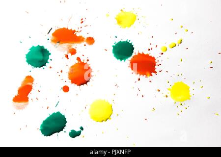 Tropfen rote, gelbe und grüne Farbe sind auf weißem Hintergrund gesprüht. Ein wunderschönes und farbenfrohes Abstraktion wird erstellt. Stockfoto