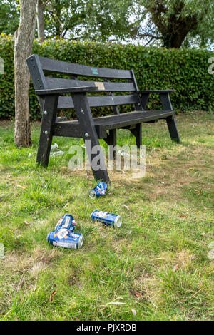 Leere Bierdosen auf Gras nächste Bank zu Park Stockfoto