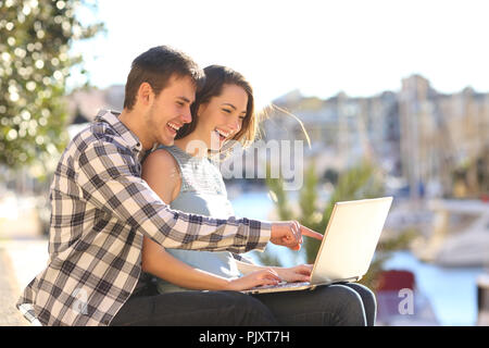 Glückliches Paar verwendet einen Laptop in einem Hafen im Sommerurlaub Stockfoto