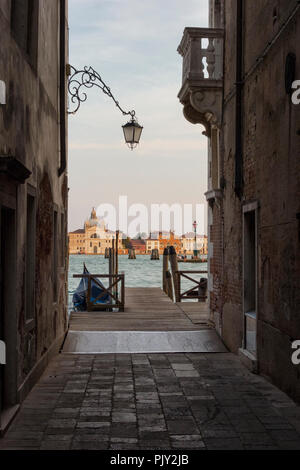 Blick aus einer Seitenstraße auf der Suche Vergangenheit eine Gondelbahn über den Canal Grande in Richtung Chiesa di Santa Maria della Presentazione und der reich verzierte Lampe an Stockfoto