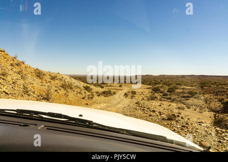 Frauenbeine gelehnt aus dem Auto stand auf Schotterpiste in der Wüste Namib, Namib-Naukluft-Nationalpark, wichtigste Reiseziel in Namibia, Afric Stockfoto