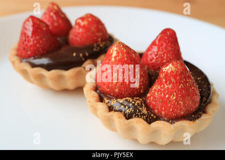 Paar Schokolade Torten gekrönt mit frischen Erdbeeren und genießbare gold Pulver serviert auf weiße Platte Stockfoto
