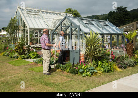 2 Männer schauen eng im Rahmen der Gewächshaus für Verkauf auf attraktive Outdoor Messestand Anzeige - RHS Chatsworth Flower Show, Derbyshire, England, Großbritannien Stockfoto