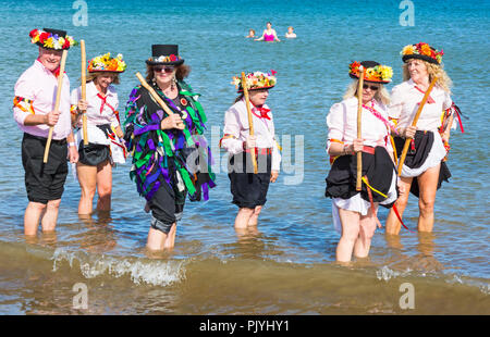 Swanage, Dorset, Großbritannien. 9. September 2018. Menschenmassen strömen zu den zweiten Tag der Swanage Folk Festival der Tanzgruppen und Musik entlang der Küste zu sehen. Herrlich warme sonnige Wetter lockte einige Tänzer im Meer, am Ende einer wunderschönen Wochenende zu tanzen. Morris Dancers, Mitglieder von Phoenix Morris tanzen im Meer mit Mitglied von Wicket Brut Grenze Morris. Credit: Carolyn Jenkins/Alamy leben Nachrichten Stockfoto