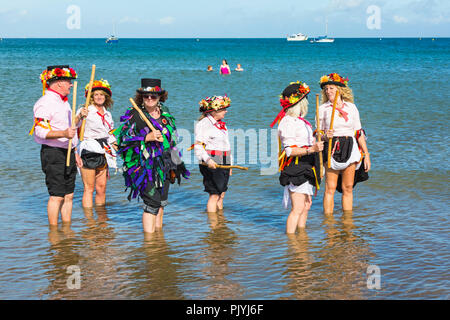 Swanage, Dorset, Großbritannien. 9. September 2018. Menschenmassen strömen zu den zweiten Tag der Swanage Folk Festival der Tanzgruppen und Musik entlang der Küste zu sehen. Herrlich warme sonnige Wetter lockte einige Tänzer im Meer, am Ende einer wunderschönen Wochenende zu tanzen. Morris Dancers, Mitglieder von Phoenix Morris tanzen im Meer mit Mitglied von Wicket Brut Grenze Morris. Credit: Carolyn Jenkins/Alamy leben Nachrichten Stockfoto