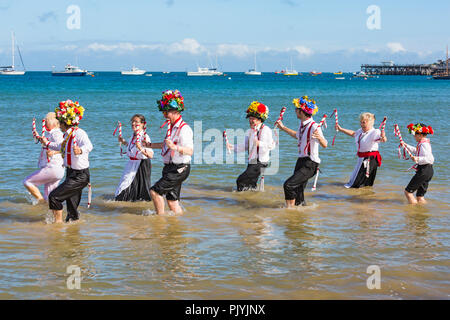 Swanage, Dorset, Großbritannien. 9. September 2018. Menschenmassen strömen zu den zweiten Tag der Swanage Folk Festival der Tanzgruppen und Musik entlang der Küste zu sehen. Herrlich warme sonnige Wetter lockte einige Tänzer im Meer, am Ende einer wunderschönen Wochenende zu tanzen. Morris Dancers, Mitglieder der Basingclog Morris tanzen im Meer. Credit: Carolyn Jenkins/Alamy leben Nachrichten Stockfoto