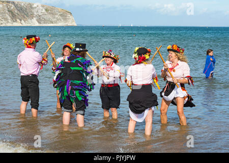 Swanage, Dorset, Großbritannien. 9. September 2018. Menschenmassen strömen zu den zweiten Tag der Swanage Folk Festival der Tanzgruppen und Musik entlang der Küste zu sehen. Herrlich warme sonnige Wetter lockte einige Tänzer im Meer, am Ende einer wunderschönen Wochenende zu tanzen. Morris Dancers, Mitglieder von Phoenix Morris tanzen im Meer mit Mitglied von Wicket Brut Grenze Morris. Credit: Carolyn Jenkins/Alamy leben Nachrichten Stockfoto