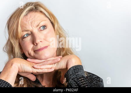 Studio Portrait Porträt von attraktiven nachdenklich im mittleren Alter blonde Frau in den Vierzigern, die Neugierigen oder Fragen Stockfoto