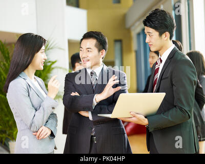 Zwei asiatische Geschäftsleute und eine Geschäftsfrau Diskussion von mit Laptop Computer in der Lobby. Stockfoto