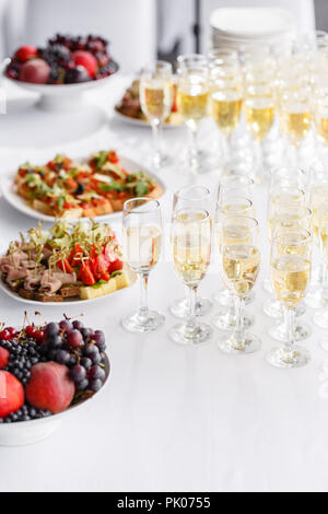 Feierlichen Rutsch ins neue Jahr und Veranstaltungsräume. Viele Gläser Champagner oder Wein auf dem Tisch im Restaurant Buffet mit vielen leckeren Snacks. Canapees, Bruschetta, und kleine Desserts auf weiße Platte Stockfoto
