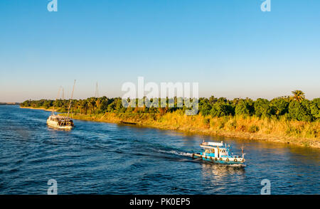 Schlepper ziehen Touristen segeln Boot flussaufwärts am späten Nachmittag Sonne, Nil, Ägypten, Afrika Stockfoto