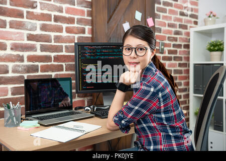 Portrait von jungen asiatischen Programmiererin sitzen in Ihrem Büro arbeiten und lächelt freundlich. Stockfoto