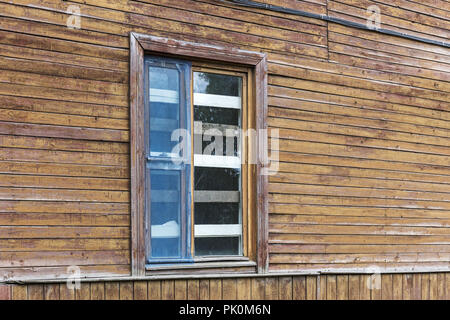 Verbrettert und zerbrochene Fenster auf dem verwitterten Holz- wand der abgebrochenen alten Haus Stockfoto