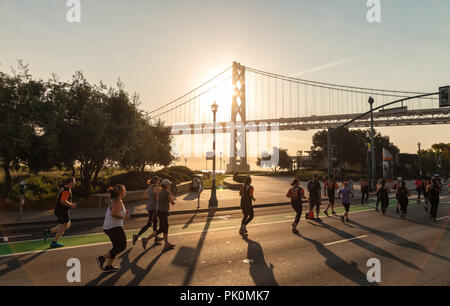 Läufer aus dem riesigen Rennen in San Francisco, Kalifornien, USA an Sept. 9, 20018, mit der Bay Bridge im Hintergrund. Stockfoto