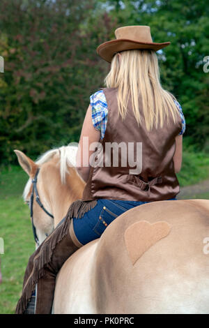 Rückansicht des Hut tragen junge Frau in Jeans sitzen ohne Sattel auf einem Pferd mit einer hübschen Herz Form auf der Rückseite der Horse Hair eingerastet Stockfoto