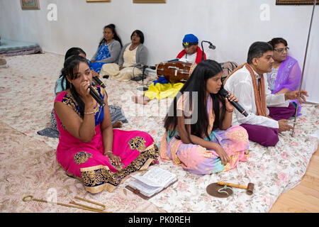 Eine kleine Gemeinde von hinduistischen Gläubigen singen während der Dienstleistungen in einem Tempel in die Keller. In Queens, New York. Stockfoto