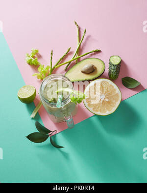 Vegetarische gesunde Smoothies aus grünem Gemüse mit grünen Blättern, Zitronenscheiben, Avocado, cocumber und Kunststoff Stroh in einer Glasschüssel auf Duplex Stockfoto