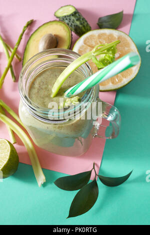 Vegetarische gesunde Smoothies aus grünem Gemüse mit grünen Blättern, Zitronenscheiben, Avocado, cocumber und Kunststoff Stroh in einer Glasschüssel auf Duplex Stockfoto