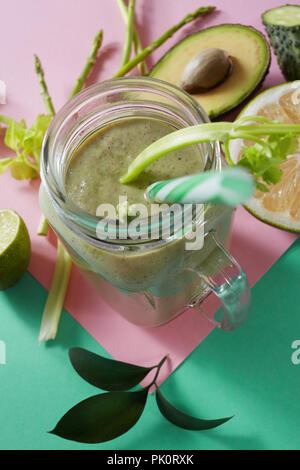 Vegetarische gesunde Smoothies aus grünem Gemüse mit grünen Blättern, Zitronenscheiben, Avocado, cocumber und Kunststoff Stroh in einer Glasschüssel auf Duplex Stockfoto