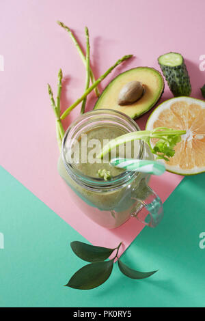 Vegetarische gesunde Smoothies aus grünem Gemüse mit grünen Blättern, Zitronenscheiben, Avocado, cocumber und Kunststoff Stroh in einer Glasschüssel auf Duplex Stockfoto