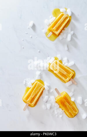 Mango Eis auf einem Stick mit Eis Schichten und spritzt auf grauem Marmor tisch mit einer Kopie des Raumes. Hausgemachte Sommer Nachtisch. Flach Stockfoto