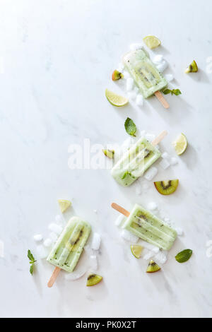 Zusammensetzung in Form von einer Ecke des Eis auf einem Stick mit einem Stück von Kiwi und Eis auf einem grauem Marmor Hintergrund. Platz für Text. Layout für Stockfoto