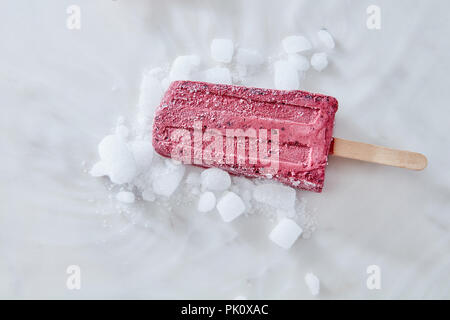 Frucht rot Eis Eis am Stiel auf einem Stock. Sommer Süßigkeiten und Desserts mit Eis auf Marmor Hintergrund. Veganes essen. Stockfoto