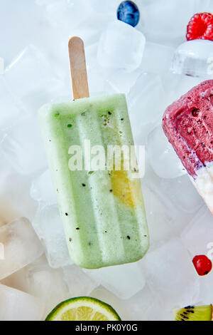 Detox, gesunden grünen Smoothie Eis am Stiel über das Eis mit Schicht Kalk, Beeren, Kiwi, flach. Sommer Stimmung. Stockfoto