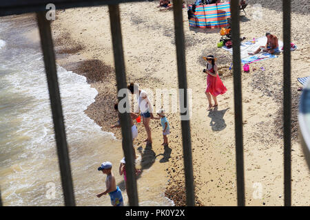 Eine junge Frau in einem hübschen Kleid fotografiert der Urlauber am Strand, Southwold, Suffolk, Großbritannien während der Hitzewelle von 2018. Stockfoto