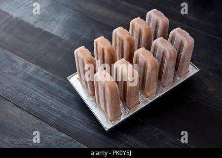 Kunststoff popsicle Eis am Stiel form Formen mit hausgemachte Schokolade ice creame und Bonbons in Eis pop Formen auf einer hölzernen Hintergrund mit Kopie Raum Stockfoto