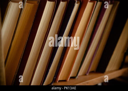 Viele alte Bücher in einer Buchhandlung oder Bibliothek. Getönten Bild. . Selektive konzentrieren. Antike Bücher stapeln. Retro Style. Vintage Bücher auf dem Bücherregal. Konzept der Schule Bank lesen. Stockfoto