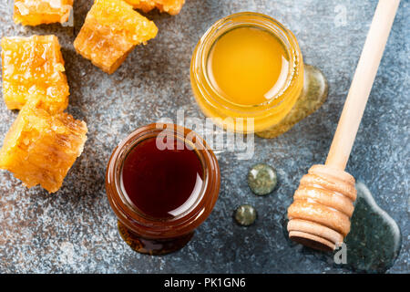 Honig im Glas und Bienenwaben. Buchweizen Honig, wilden Honig und Waben auf konkreten Hintergrund, Ansicht von oben Stockfoto