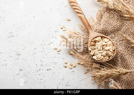 Haferflocken und Ähren auf konkreten Hintergrund mit Platz für Text kopieren Stockfoto