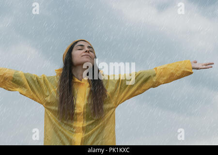 Frau tragen gelbe Regenmantel Regen aus Stockfoto