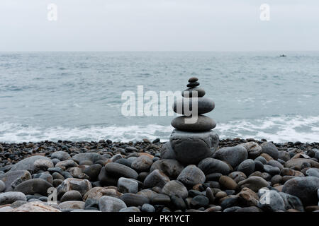 Stapel von Kiesel auf einem großen Felsen am Strand auf dem Ozean Hintergrund Stockfoto